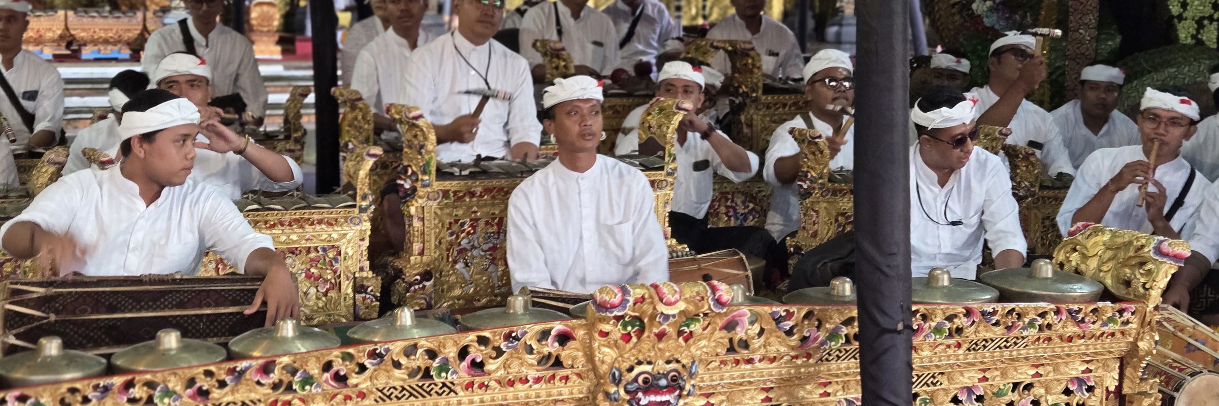 Traditional Balinese gamelan musicians performing at a temple ceremony in Ubud, Bali, wearing ceremonial white attire. 