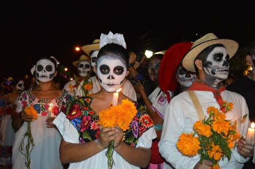 Traditional Day of the Dead parade with face paint, marigolds, and colourful attire honoring Mexican ancestors. 
