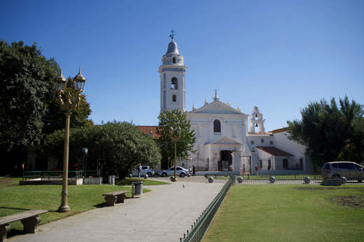 A historic white colonial church with bell tower and a peaceful garden square, reflecting Mexico's colonial heritage. 
