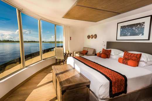 Expedition cruise in the stunning corner suite with expansive views of the rainforest