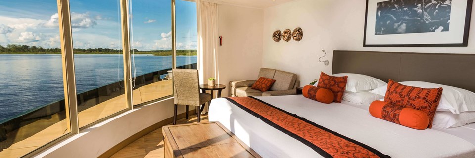 Expedition cruise in the stunning corner suite with expansive views of the rainforest