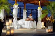 Romantic spa cabana at Fairmont Mayakoba in Riviera Maya with white drapes, candlelight, and tropical palm setting. 