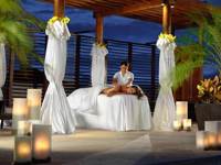 Romantic spa cabana at Fairmont Mayakoba in Riviera Maya with white drapes, candlelight, and tropical palm setting. 