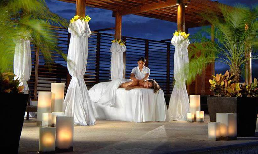 Romantic spa cabana at Fairmont Mayakoba in Riviera Maya with white drapes, candlelight, and tropical palm setting. 