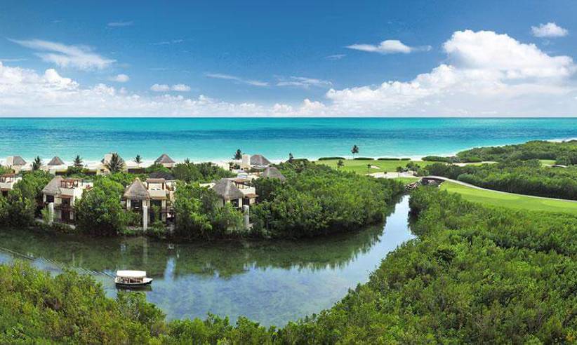 Aerial view of Fairmont Mayakoba Resort in Riviera Maya showing mangroves, water canals, villas, and the Caribbean Sea. 