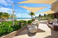 Beachfront outdoor lounge with modern seating and sunshades at Catalonia Playa Maroma Resort, Riviera Maya, Mexico. 
