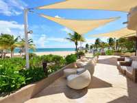 Beachfront outdoor lounge with modern seating and sunshades at Catalonia Playa Maroma Resort, Riviera Maya, Mexico. 