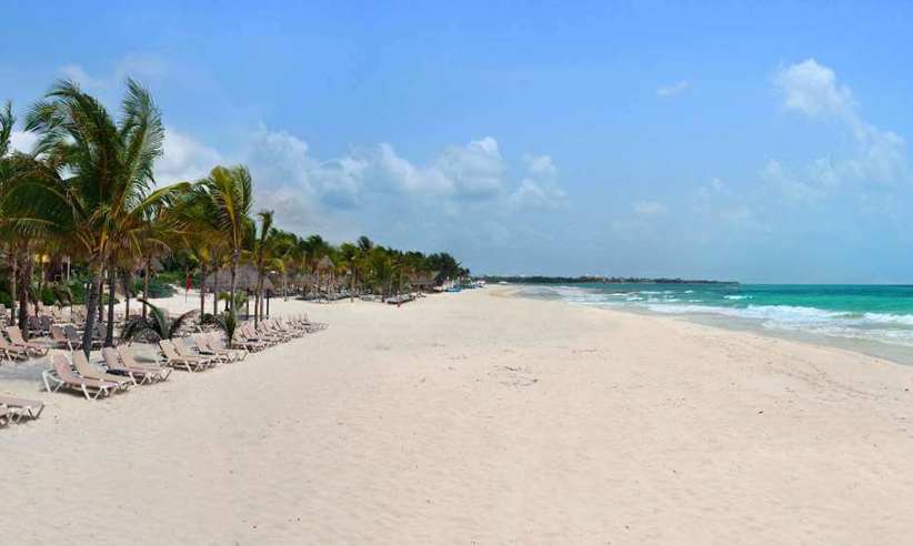 Wide white sand beach lined with palm trees and turquoise waters at Catalonia Playa Maroma Resort, Riviera Maya, Mexico. 
