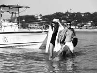 Stylish couple stepping off a boat in Buzios, Brazil, evoking a luxury and romantic beach getaway. 