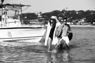 Stylish couple stepping off a boat in Buzios, Brazil, evoking a luxury and romantic beach getaway. 