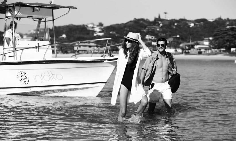 Stylish couple stepping off a boat in Buzios, Brazil, evoking a luxury and romantic beach getaway. 