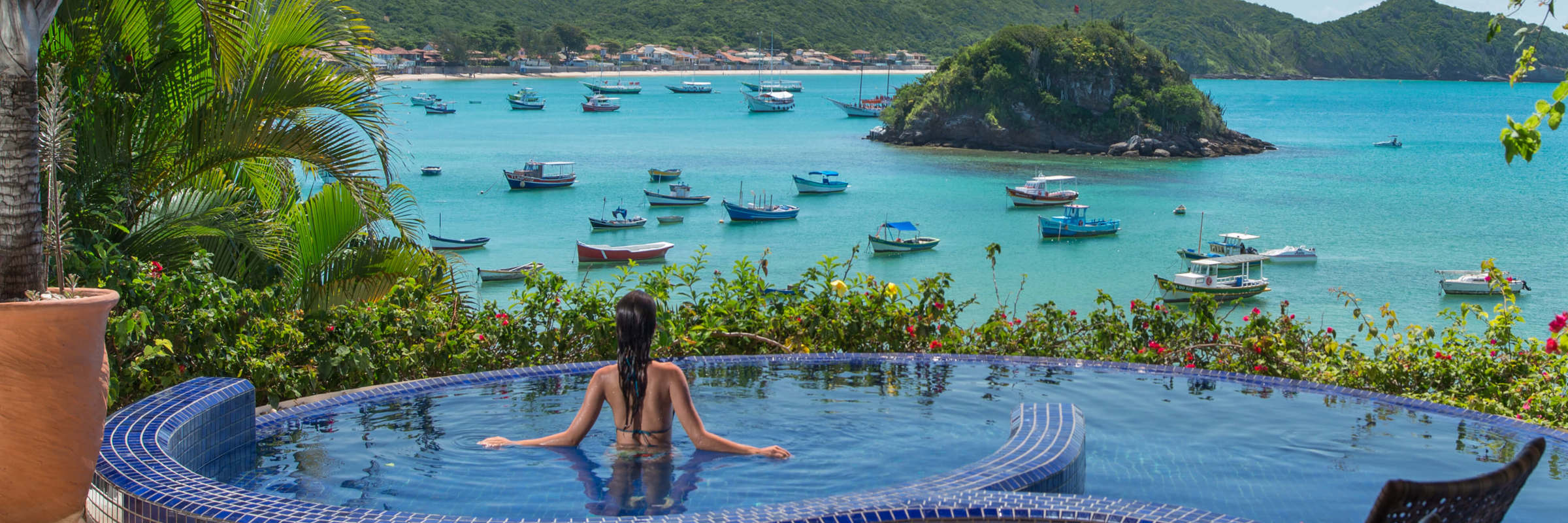 Infinity pool at Villa d'Este, Buzios, with panoramic views over Armacao Bay and anchored boats. 