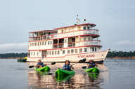 Guests kayaking on the Amazon River with the Tucano expedition cruise boat in the background. 