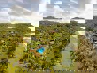 Aerial view of a secluded coastal lodge surrounded by dense tropical forest. 
