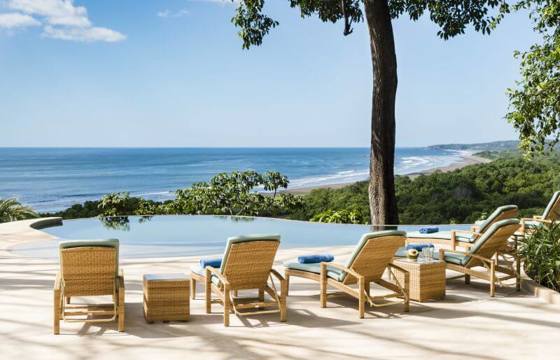 Lounge chairs line an infinity pool overlooking the Pacific, offering a tranquil setting at Lagarta Lodge. 