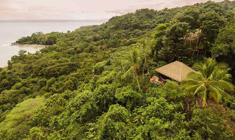 An eco-lodge at Lapa Rios peeks through dense rainforest, offering sweeping views of the Osa Peninsula coastline. 