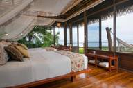 A stylish oceanview suite at Playa Cativo Lodge, featuring canopy bed, hardwood floors, and tropical charm. 