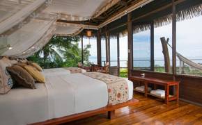 A stylish oceanview suite at Playa Cativo Lodge, featuring canopy bed, hardwood floors, and tropical charm. 