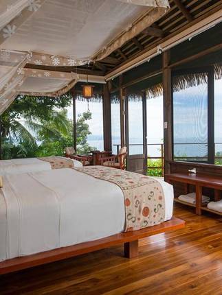 A stylish oceanview suite at Playa Cativo Lodge, featuring canopy bed, hardwood floors, and tropical charm. 