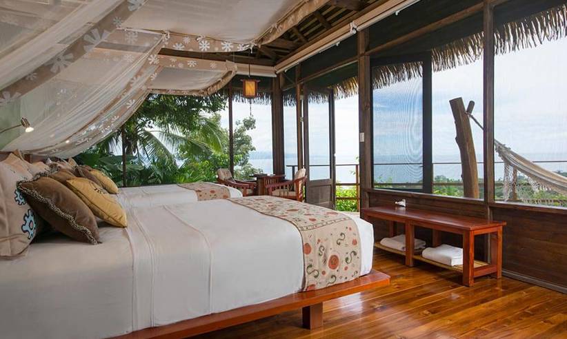A stylish oceanview suite at Playa Cativo Lodge, featuring canopy bed, hardwood floors, and tropical charm. 