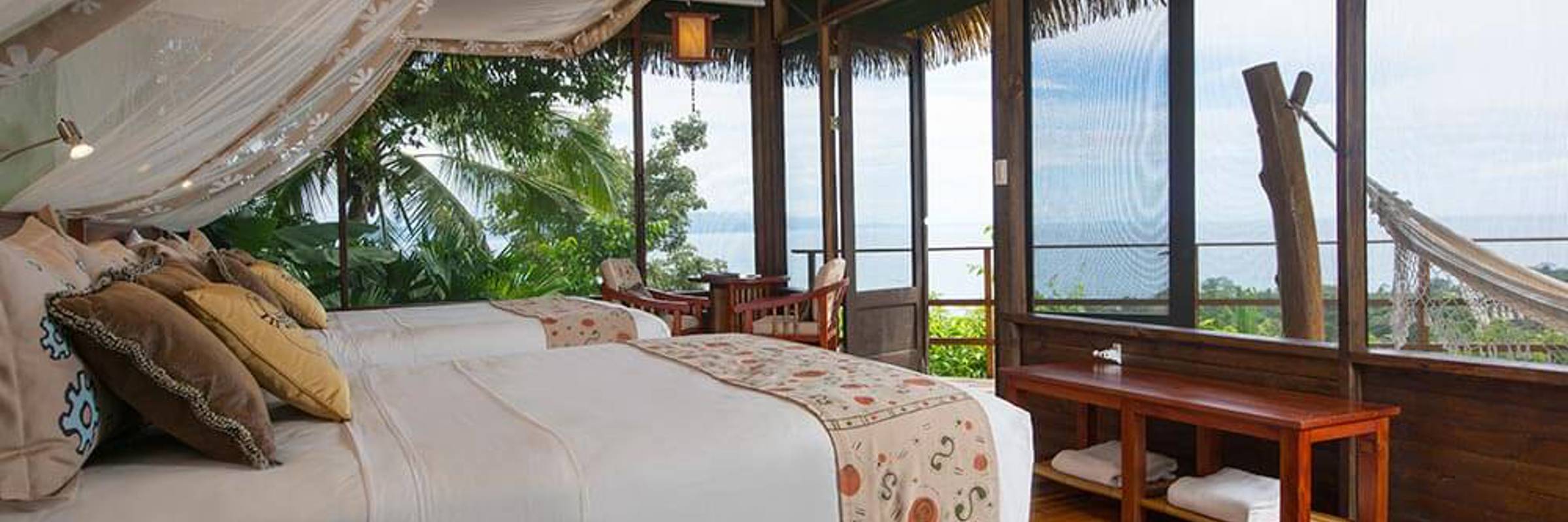 A stylish oceanview suite at Playa Cativo Lodge, featuring canopy bed, hardwood floors, and tropical charm. 