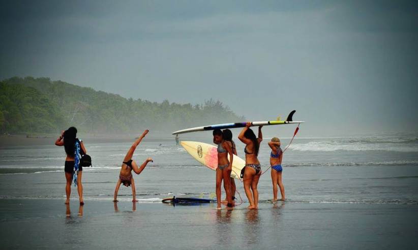 Tourists Surfers on the wide, tranquil beach of Playa Esterillos on Costa Rica's Pacific coast. 