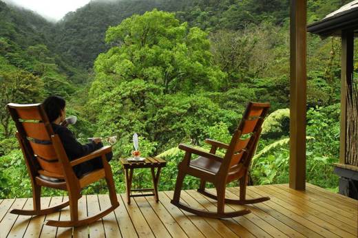 Guest relaxing on wooden terrace surrounded by lush cloud forest in Bajos del Toro. 