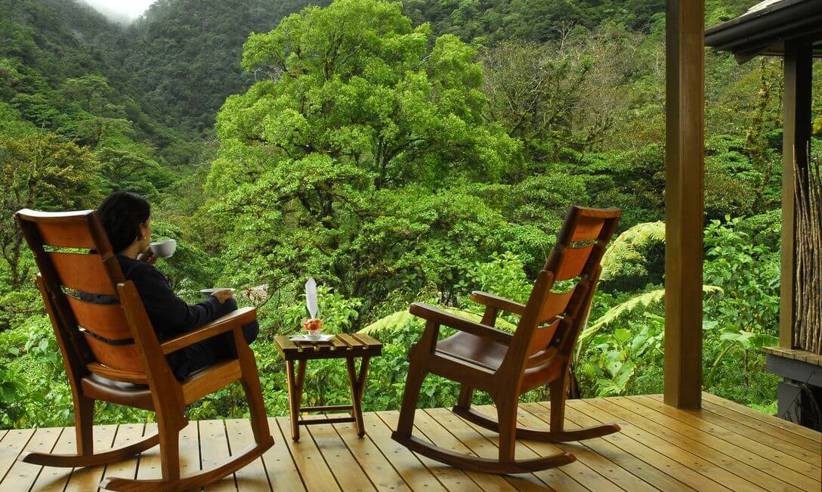 Guest relaxing on wooden terrace surrounded by lush cloud forest in Bajos del Toro. 
