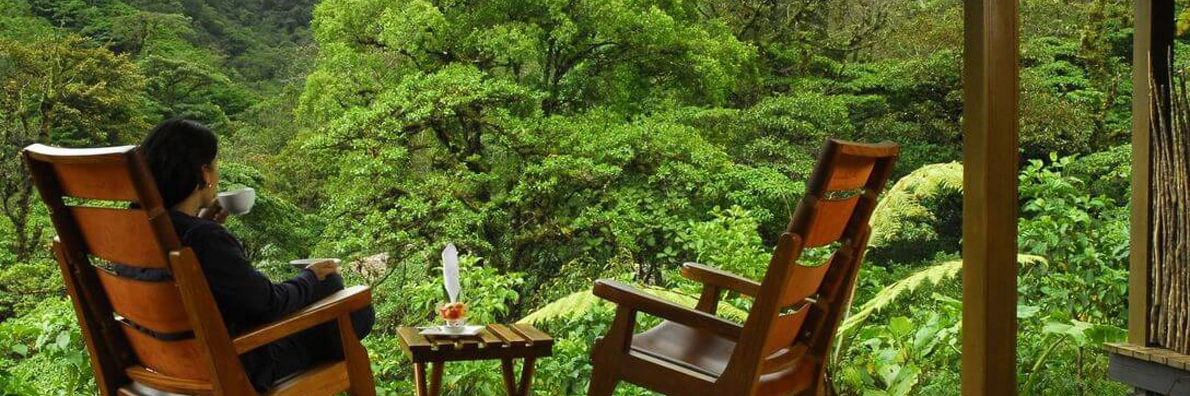 Guest relaxing on wooden terrace surrounded by lush cloud forest in Bajos del Toro. 