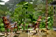 Guest relaxing on wooden terrace surrounded by lush cloud forest in Bajos del Toro. 