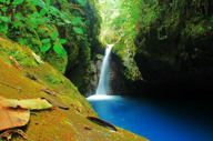 Secluded waterfall pool surrounded by mossy rocks and dense rainforest in Bajos del Toro. 