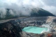 Mist rises above the vivid crater lake of Poas Volcano, striking geothermal wonder in Costa Rica. 