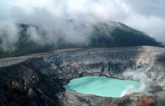 Mist rises above the vivid crater lake of Poas Volcano, striking geothermal wonder in Costa Rica. 