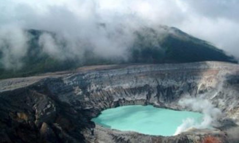 Mist rises above the vivid crater lake of Poas Volcano, striking geothermal wonder in Costa Rica. 