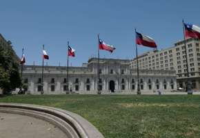 La Moneda Palace in Santiago, Chile framed by waving national flags on a clear day in the capital's civic center. 