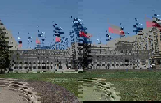 La Moneda Palace in Santiago, Chile framed by waving national flags on a clear day in the capital's civic center. 