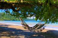 A hammock sways in the shade, overlooking the tranquil beach and turquoise waters of Playa Cativo. 