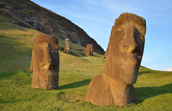 Ancient Moai statues partially buried on the grassy slopes of Rano Raraku, the volcanic quarry on Easter Island where these iconic figures were carved centuries ago. 