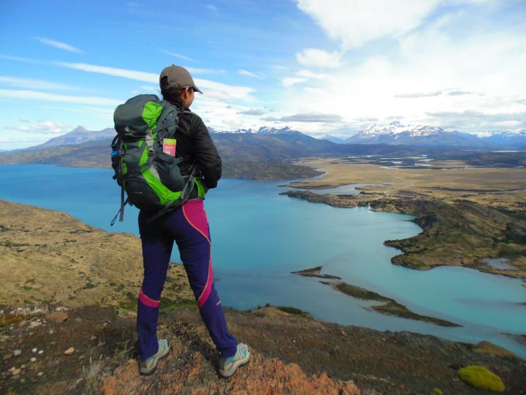 Hiker overlooking turquoise lake and vast Patagonia landscape in Torres del Paine National Park, Chile.
