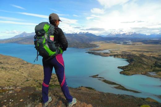 Hiker overlooking turquoise lake and vast Patagonia landscape in Torres del Paine National Park, Chile.