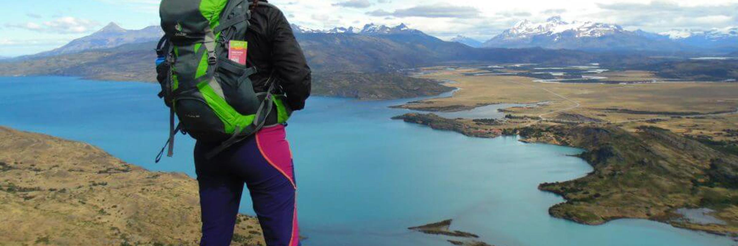 Hiker overlooking turquoise lake and vast Patagonia landscape in Torres del Paine National Park, Chile.