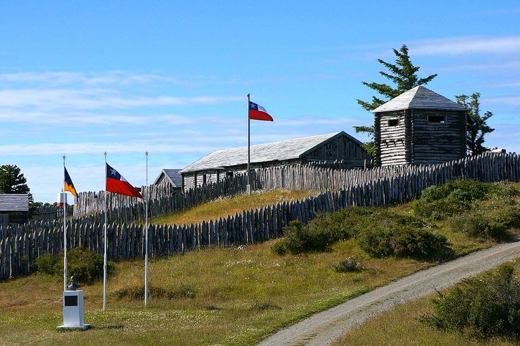 A reconstructed wooden fort with flags flying marks the historic site of Fort Bulnes near Puerto de Hambre southern Chile. 