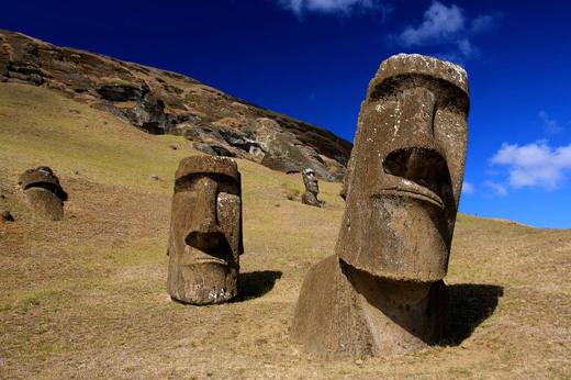 Moai statues at Rano Raraku quarry on Easter Island under a deep, surrounded by grass slopes. 