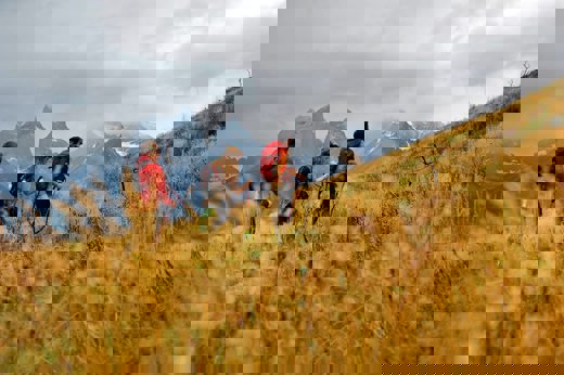 Group of trekkers hiking the W Trek in Torres del Paine with dramatic mountain peaks in the distance. 