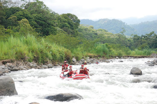 Group navigating white-water rapids on a rafting adventure through lush Costa Rican wilderness. 