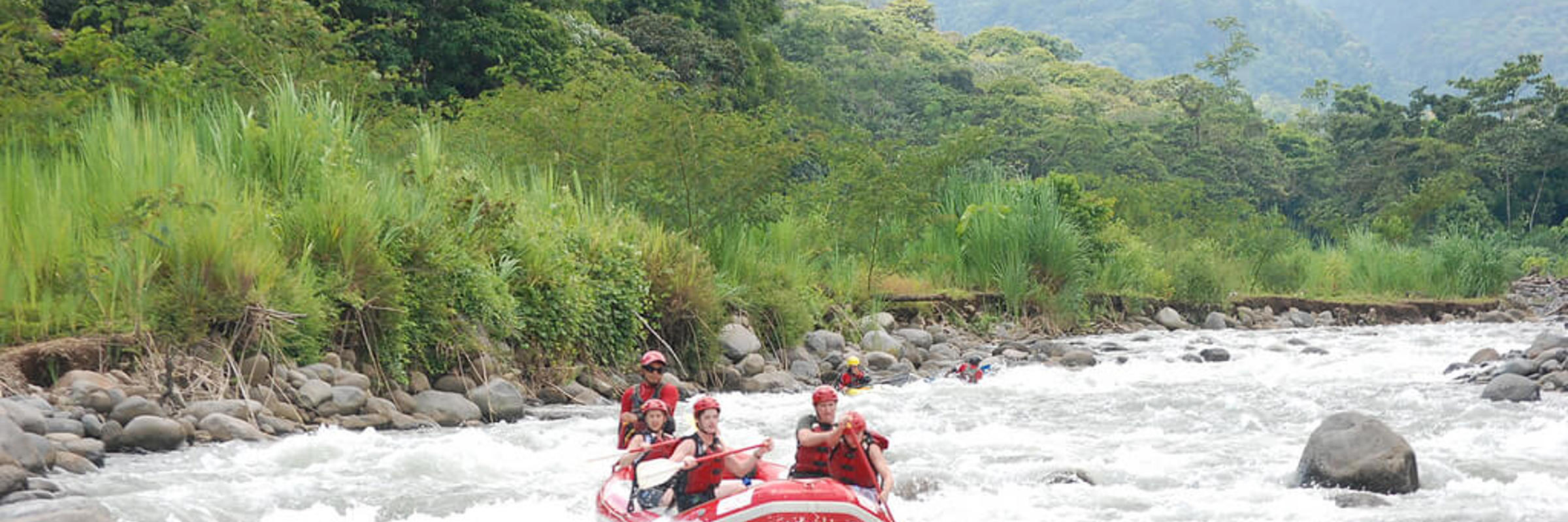 Group navigating white-water rapids on a rafting adventure through lush Costa Rican wilderness. 