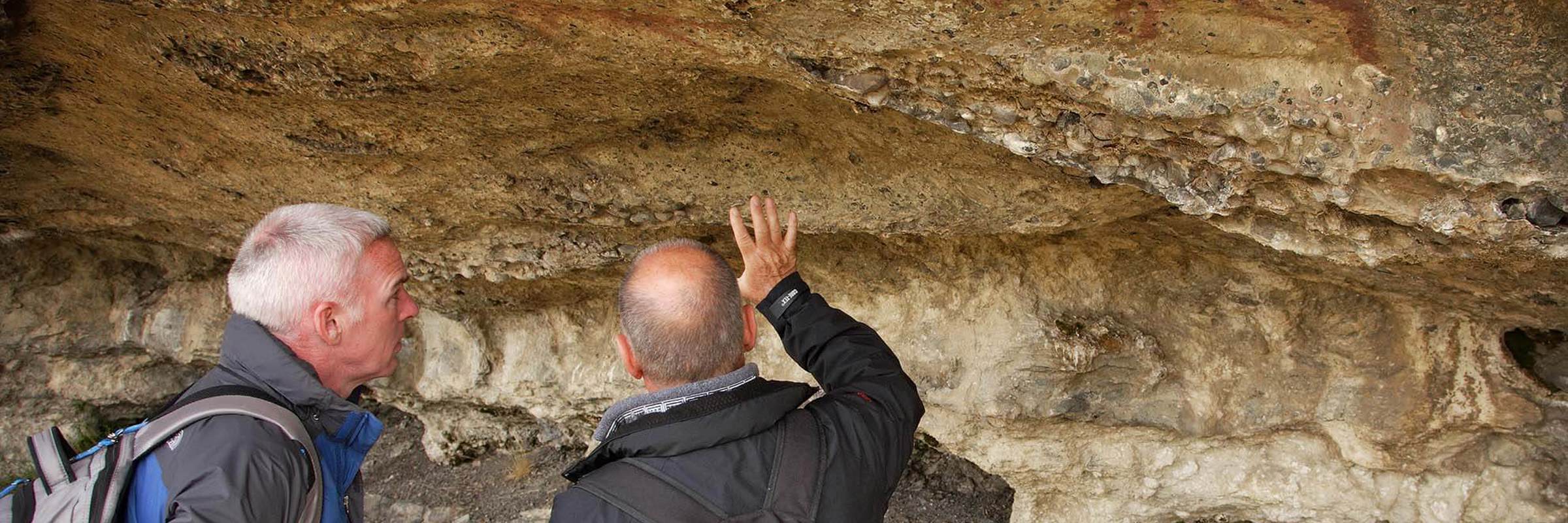 Two men examine ancient Aonikenk cave paintings in Patagonia on a cultural heritage hike near Torres del Paine, Chile. 