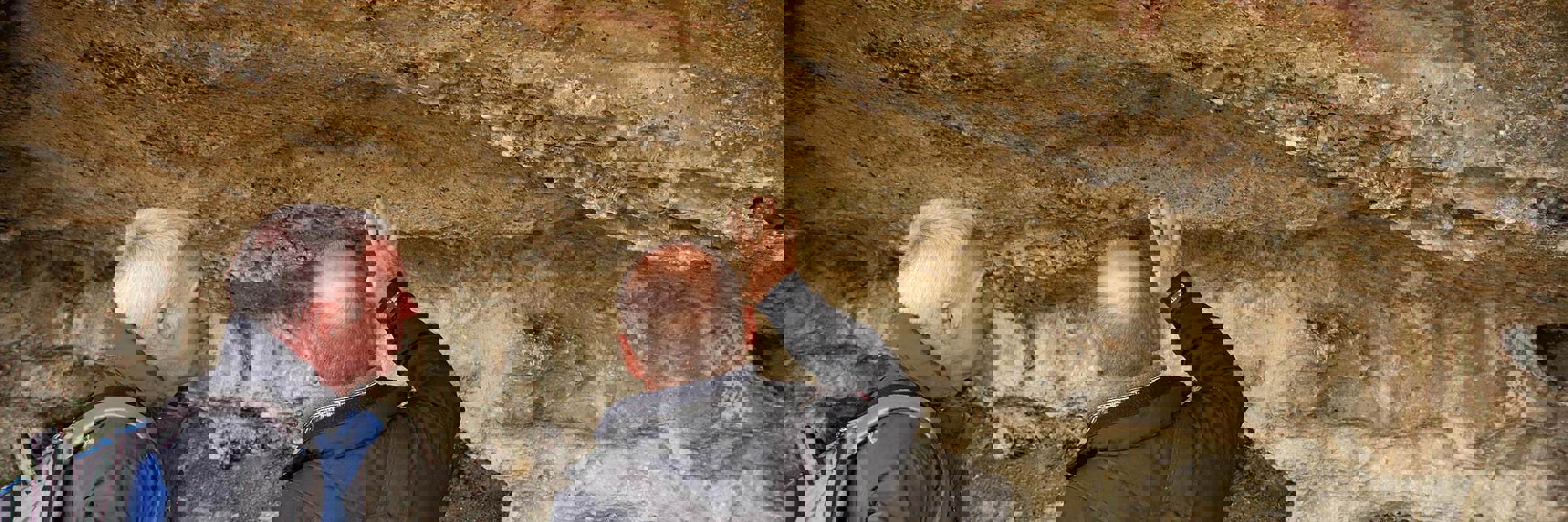 Two men examine ancient Aonikenk cave paintings in Patagonia on a cultural heritage hike near Torres del Paine, Chile. 
