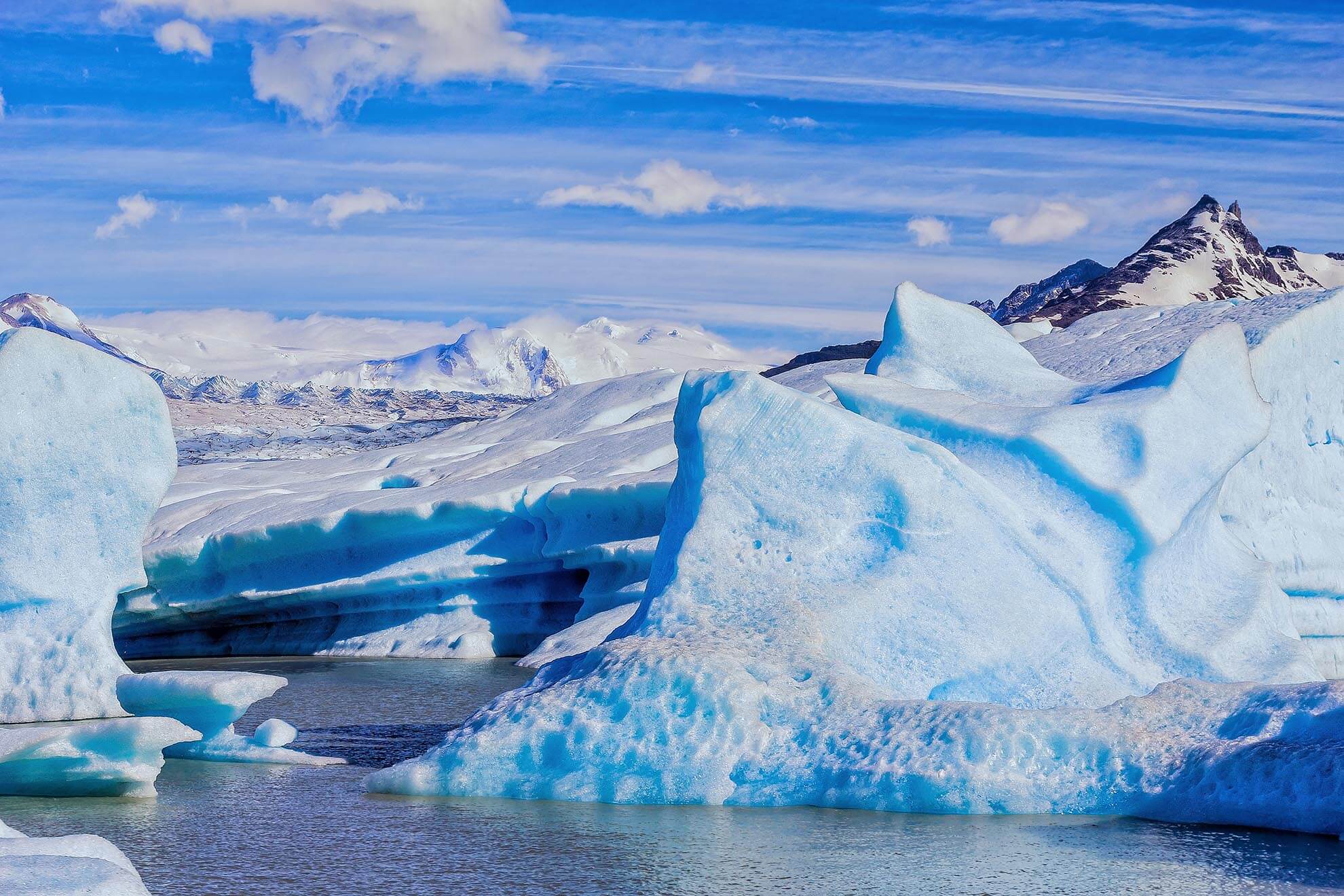 Vivid blue ice formations of Glacier Grey with snow-capped peaks in Torres del Paine National Park, Patagonia. 