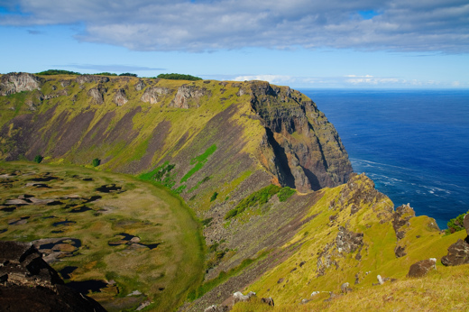 Scenic view of Rano Kau crater with steep cliffs and Pacific Ocean backdrop on Easter Island. 